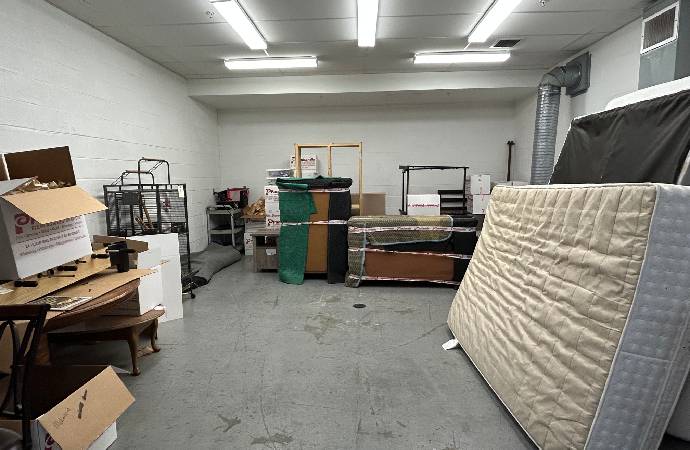 Stored customer belongings — mattresses, furniture, and boxes — held in a contractor’s storage room