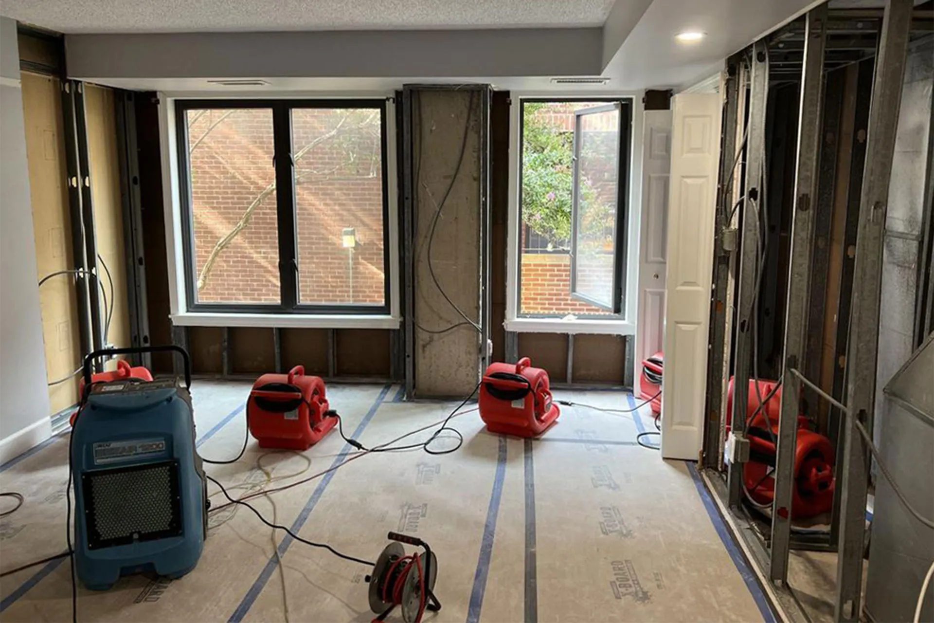 A water-damage drying setup with air movers and a dehumidifier running in a gutted room — restoration and radon insurance in Delaware