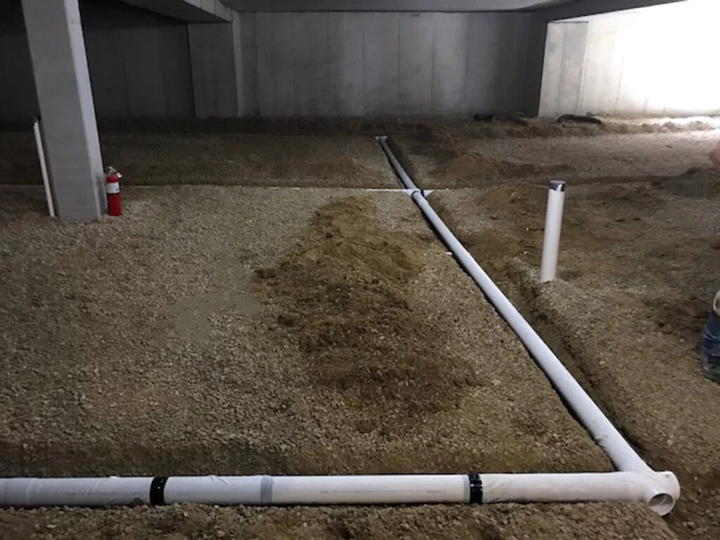 Radon sub-slab piping laid across a gravel crawlspace during a system installation — radon mitigation insurance in Florida
