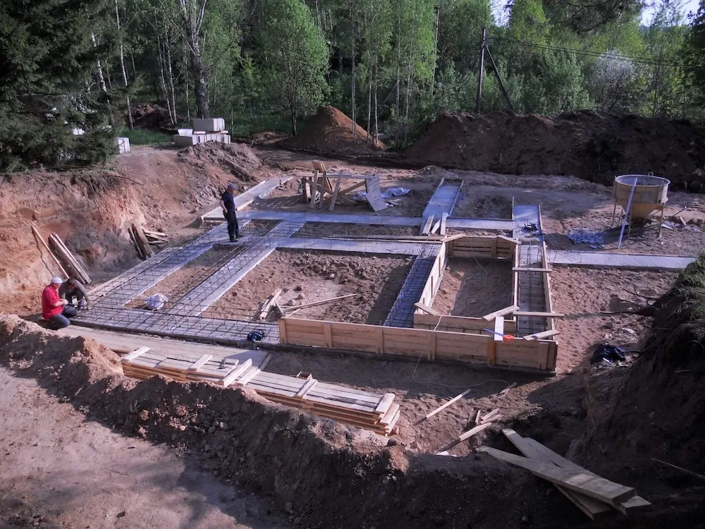 Workers preparing a new-home foundation with rebar formwork and footings — radon mitigation insurance in Florida