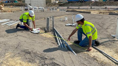 Workers measuring and laying sub-slab piping runs at a construction site — radon mitigation insurance in Connecticut