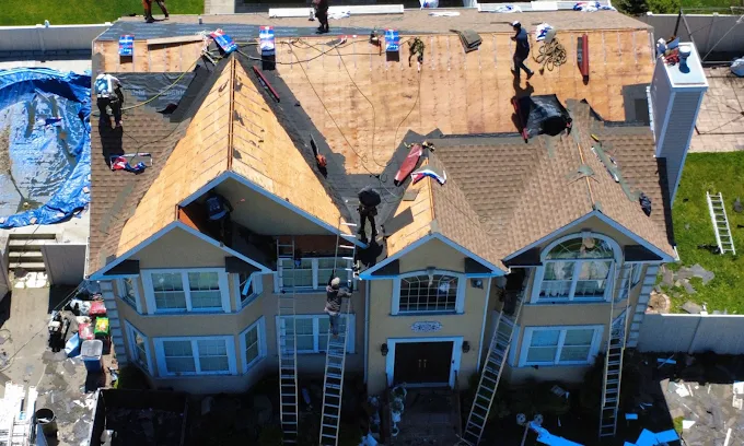 An aerial view of a crew replacing storm-damaged roof decking on a two-story house — restoration contractor insurance in Nevada