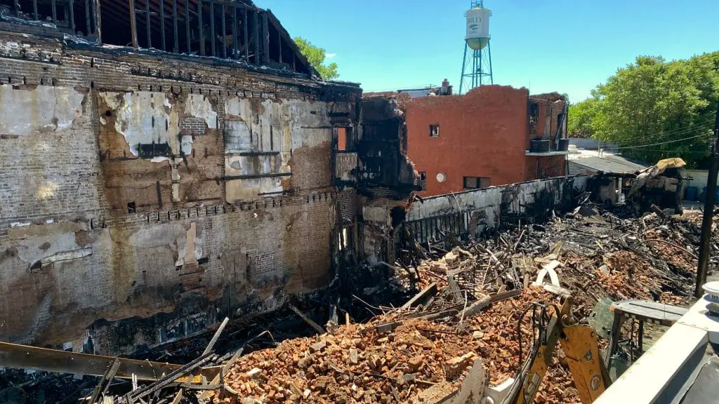 A fire-damaged commercial brick building with a collapsed roof and charred debris — restoration contractor insurance in Indiana